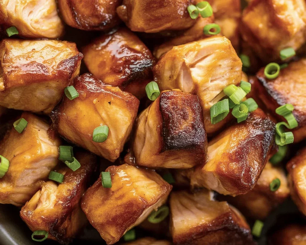 Crispy Bang Bang Salmon Bites served with a spicy sauce and garnished for flavor.